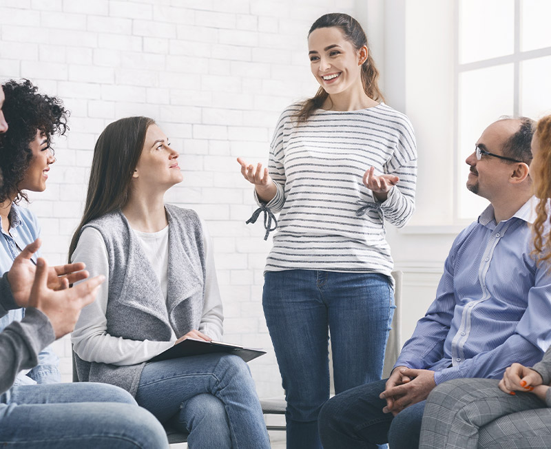 Woman sharing her progres with group on therapy session in rehab