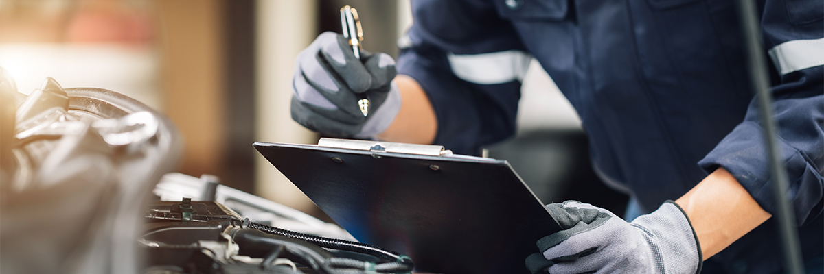 Service tech writing on a clipboard for a transmission inspection