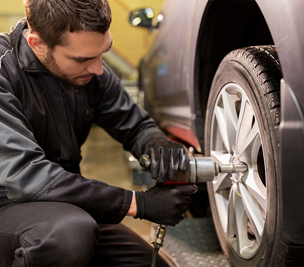 Service tech putting a tire back on a vehicle